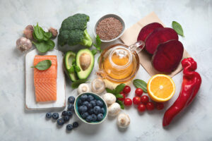 An overhead view of foods that help blood flow displayed on a nice countertop, including cayenne pepper, avocado, berries, and fish.